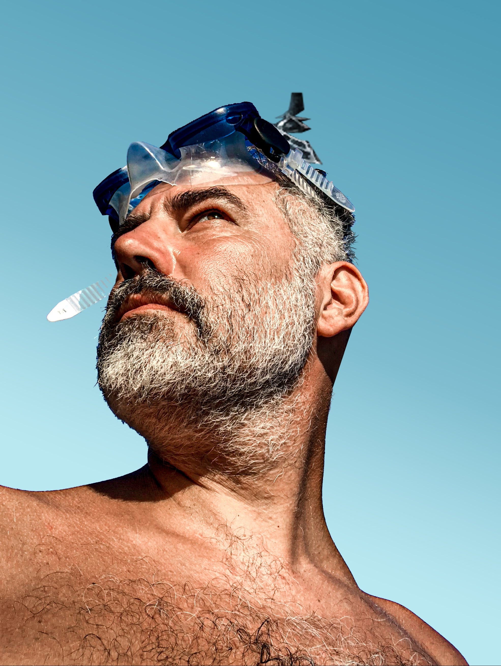 Man with a beard wearing a snorkeling mask against a clear blue sky