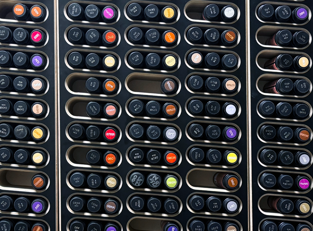 A close-up view of multiple rows of professional hair color bottles arranged in a black organizer, showing many different colors and shades.