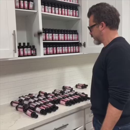 A salon owner watching their har dye bottles pour out of their dispensary's cabinet because their color bar has no hair color bottle organizer.